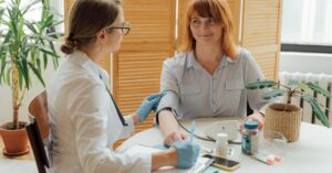 Doctor measuring patient's blood pressure with digital monitor in a clinical setting.