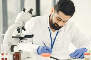 Male scientist in a laboratory, examining samples and taking notes.